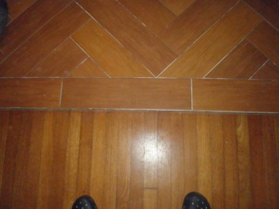 transition between herringbone plank tile floor and hardwood
